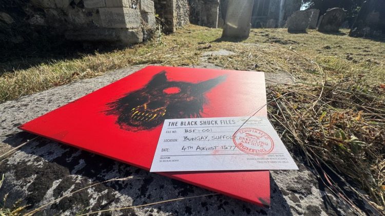 Black Shuck record cover on the ground featuring a menancing black dog against a bright red background