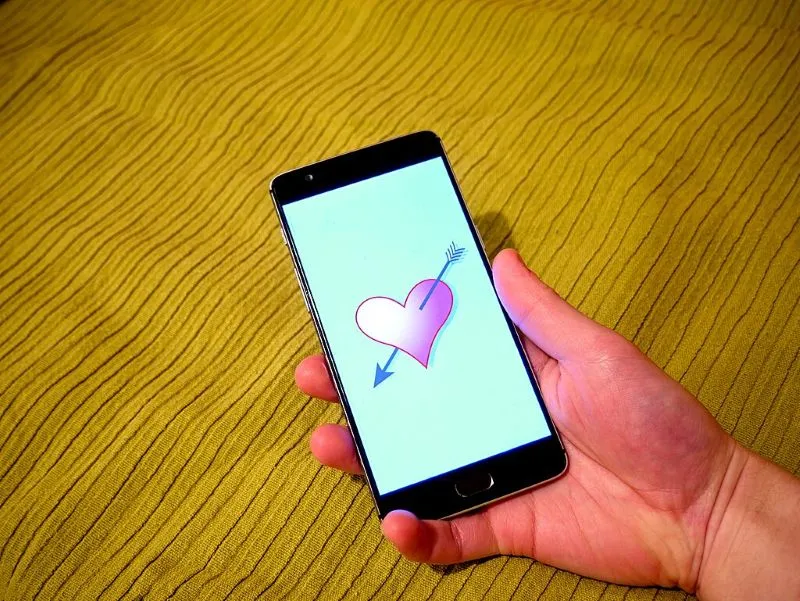 Hand holding a smartphone with a dating app on it