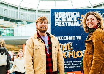 Two young people in the Forum standing in front of a "Welcome to the Explorium" sign