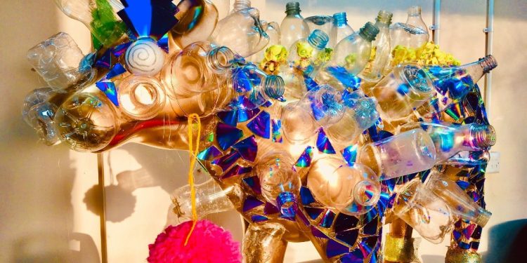 A golden cow covered in bits of plastic bottles, part of the Cows in Cambridge art installation