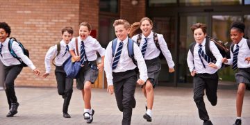 A group of school children in uniform, aged around 12 or 13, running out of school